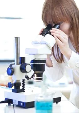 Pretty female researcher using a microscope in a lab 스톡 사진