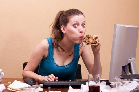 Pretty female student eats a piece of pizza 库存照片