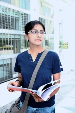 Pretty female student reading while walking. Stock Photos