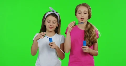 Pretty female teens having fun while blowing soap bubbles on the green screen 스톡 동영상 89947429