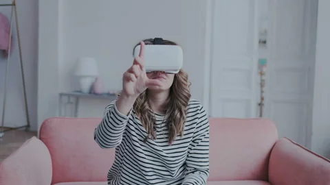 Pretty funny girl exploring a virtual reality glasses indoor. She moves her Stock Footage 106489039
