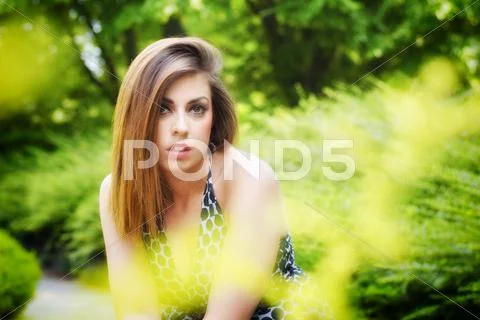Pretty girl among flowers and green plants Stock Photos