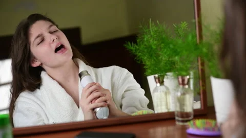 A pretty girl are singing while using the hair dryer, enjoing her life Stock Footage 146080208
