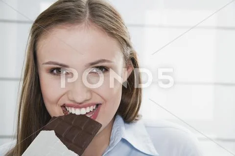 Pretty girl biting a chocolate bar Stock Photos