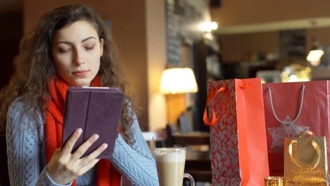 Pretty girl browsing internet on tablet in the festive cafe, steadycam shot Stock-Footage 70804901