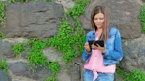 Pretty girl in a cotton jacket using tablet computer with earphones.  Stock Footage 80053404