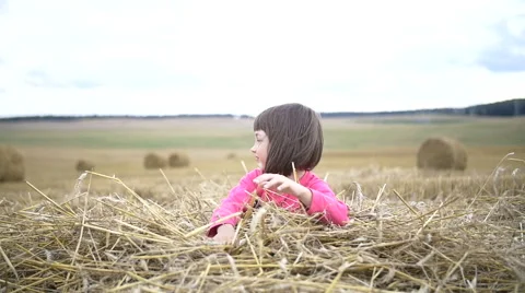 Pretty girl dabbles with a straw and smiling in a field Stock Footage