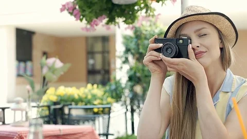 Pretty girl doing photos on old camera in the cafe's garden and drinking juice, Stock Footage