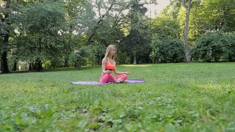 Pretty girl doing yoga and pilates in the park in the sunny morning. Stock Footage