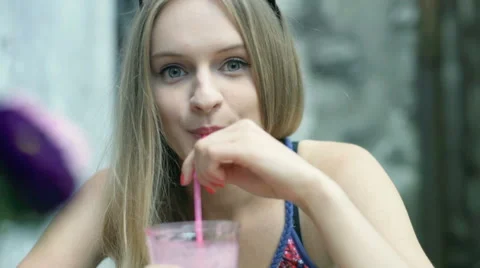 Pretty girl drinking fruity cocktail and smiling to the camera Stock Footage