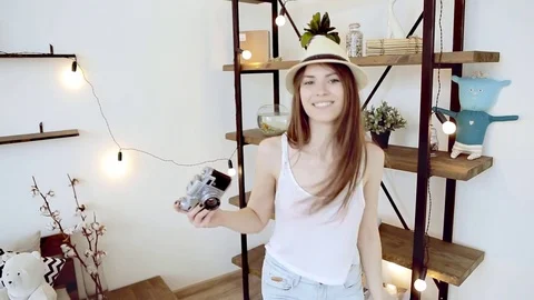 Pretty girl hipster in hat with retro camera having fun at home Stock Footage