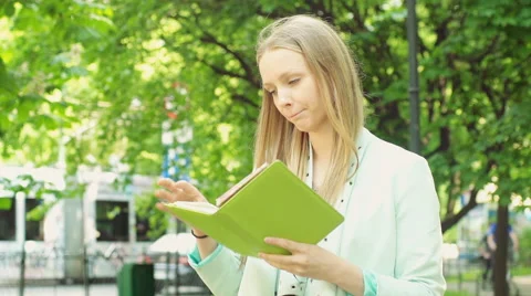 Pretty girl holding notebook and looking for something in it 스톡 동영상 66589953