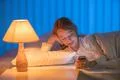 The pretty girl lay on the bed and phone. Evening night time Photo