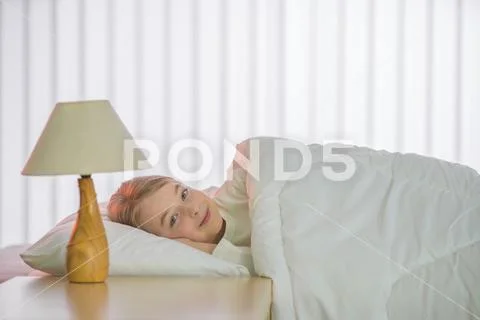 The pretty girl lay on the bed with white linens Stock Photos