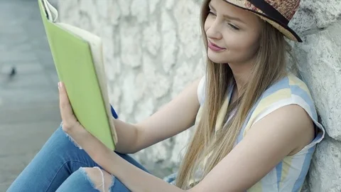 Pretty girl leaning on the stone wall and writing thoughts in her diary, steadyc Stock Footage