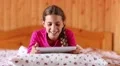 Pretty girl lies on the bed and communicates via tablet computer HD Footage