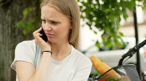Pretty girl looking irritated while talking on cellphone, steadycam shot Stock Footage