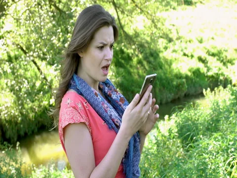 Pretty girl looks shocked while checking news on smartphone, steadycam shot Stock Footage
