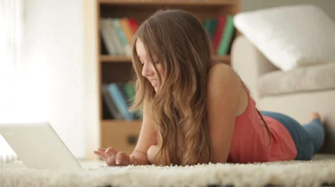 Pretty girl lying on floor using laptop looking at camera and smiling Stock Footage 34436920