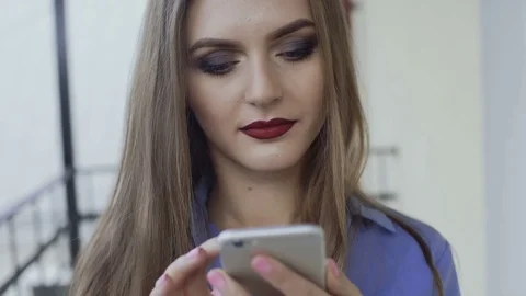 Pretty girl with make-up using smartphone on a balcony 4K Stock-Footage 81980733