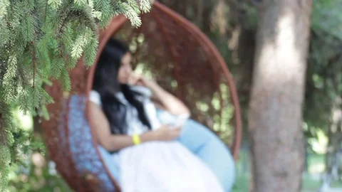 Pretty girl in park on swing, using smartphone Stock Footage