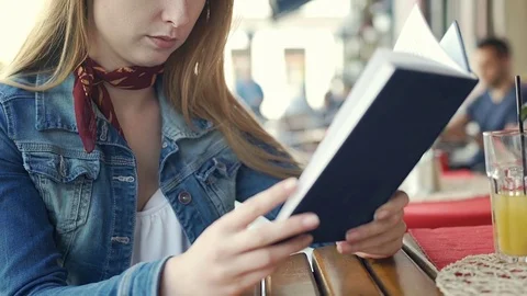 Pretty girl receives message on smartphone while reading book, steadycam shot Stock Footage