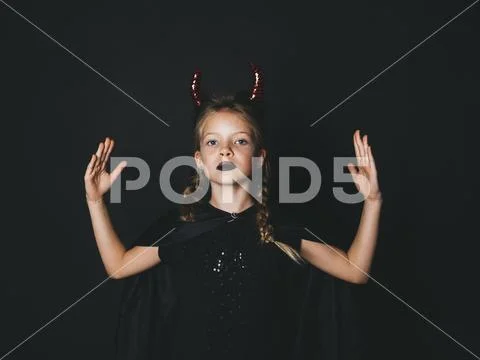 Pretty girl with red halloween horns and cape Stock Photos