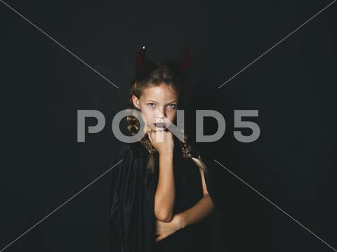 Pretty girl with red halloween horns and cape Stock Photos