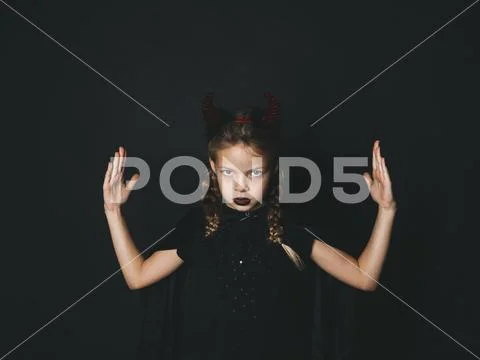 Pretty girl with red halloween horns and cape Stock Photos