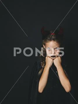 Pretty girl with red halloween horns and cape Stock Photos