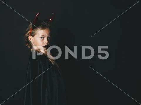 Pretty girl with red halloween horns and cape Stock Photos