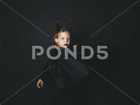 Pretty girl with red halloween horns and cape Stock Photos