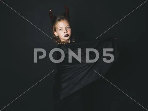 Pretty girl with red halloween horns and cape Stock Photos