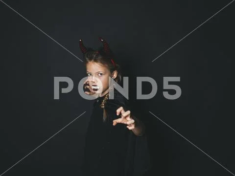 Pretty girl with red halloween horns and cape Stock Photos