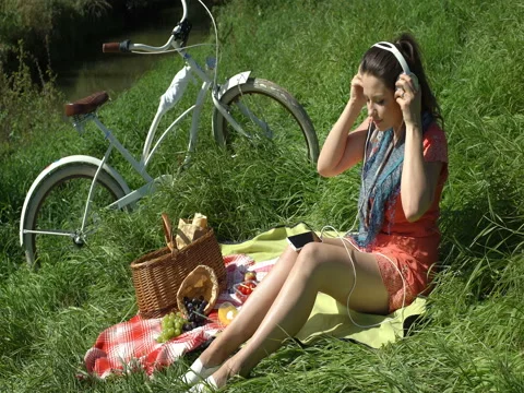 Pretty girl relaxing on the blanket on countryside and listening music, steadyca Stock Footage