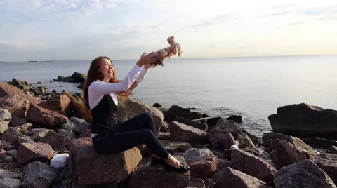 Pretty girl sit on shore front throw up and catch cute fluffy toy, slow motion Stock Footage