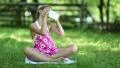 Pretty girl sits on the grass and makes selfie on his smartphone HD Footage