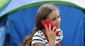 Pretty girl sits on grass near tourist tent and speaks on cell phone HD Footage