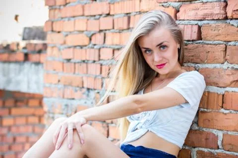 Pretty girl sitting at the brick wall Stock Photos