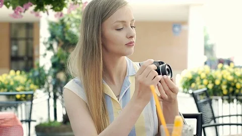 Pretty girl sitting in the cafe's garden and doing photos on old camera, steadyc Stock Footage