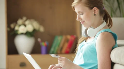Pretty girl sitting on floor using laptop holding credit card looking at came Stock Footage 34832531