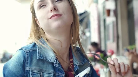 Pretty girl sitting in the outdoor cafe on windy day and eating lunch, steadycam Stock Footage