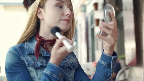 Pretty girl sitting in the outdoor cafe and improving her makeup, steadycam shot Stock Footage