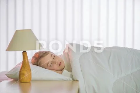 The pretty girl sleeping on the bed with white linens Stock Photos
