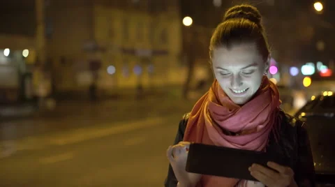 Pretty girl smiling, using tablet at night on the street. 4K 스톡 동영상 60669253