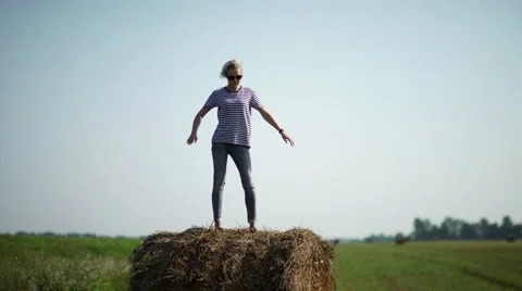 Pretty girl is standing on haystacks Stock Footage
