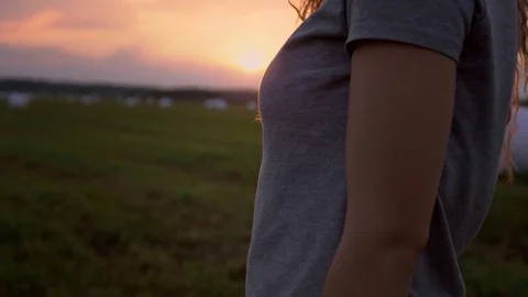 Pretty girl standing at sunset on the field Stock Footage 80344810