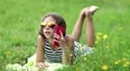 Pretty girl in sunglasses with red smartphone lies on the grass HD Footage