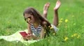 Pretty girl in sunglasses with red smartphone lies on the grass HD Footage