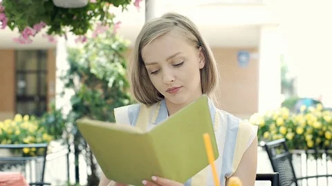 Pretty girl takes notebook from her backpack and reading it in the cafe, steadyc Stock Footage